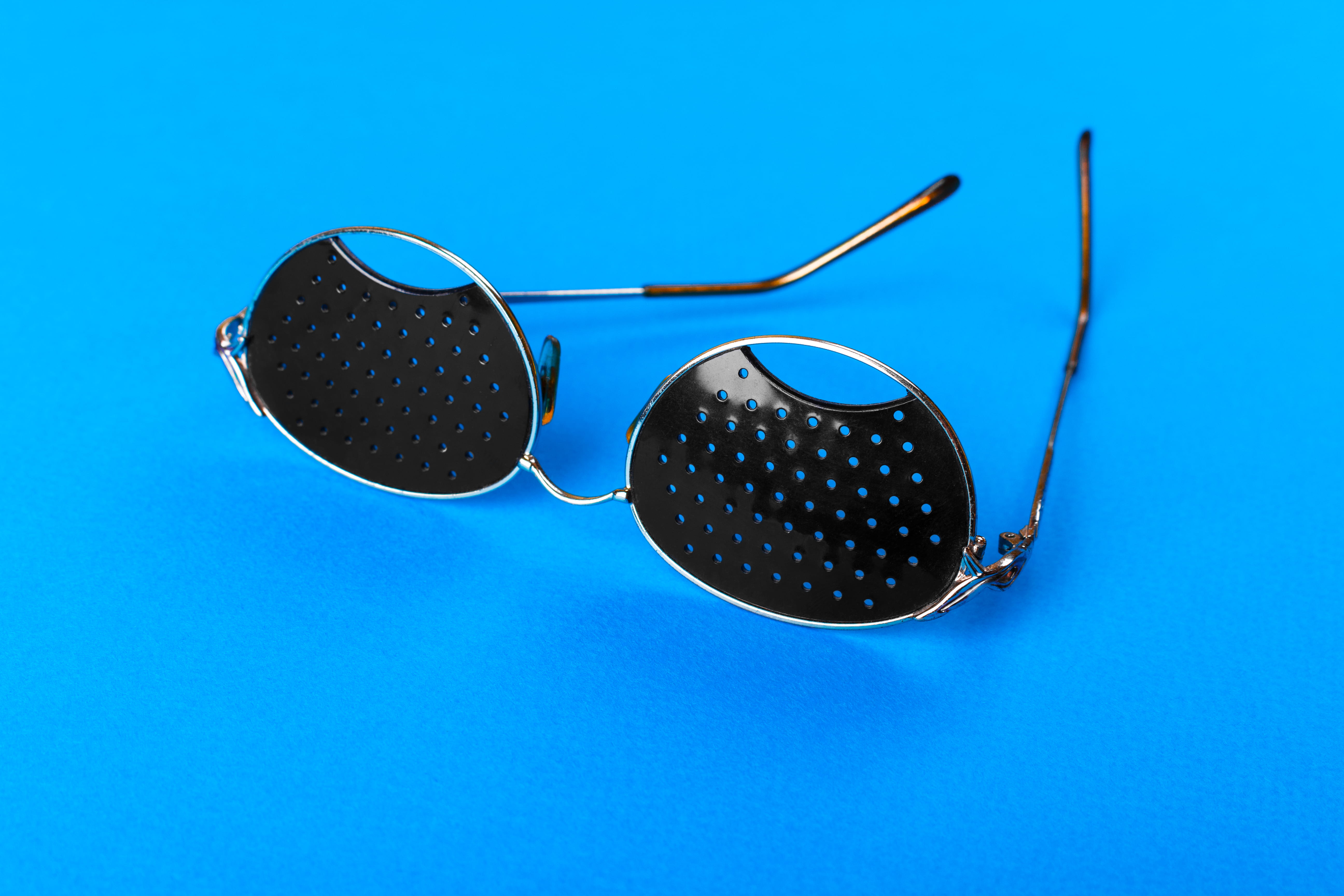Primer plano de lentes estenopeicas sobre una mesa junto a un mapa de Las Palmas y gafas tradicionales.